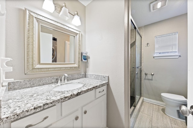 bathroom with stacked washer and dryer, vanity, toilet, and walk in shower