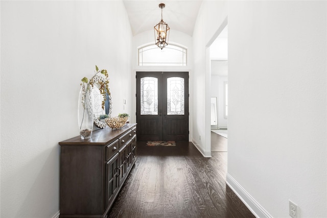 foyer featuring lofted ceiling, dark hardwood / wood-style floors, a notable chandelier, and french doors