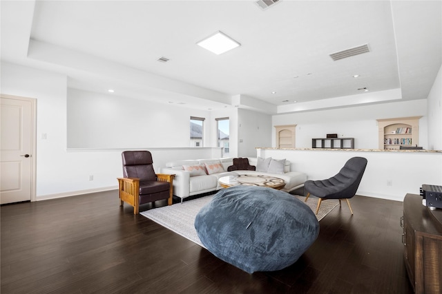 living room with dark wood-type flooring and a raised ceiling