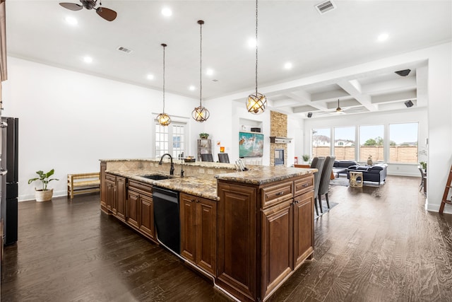 kitchen featuring a large island, sink, black dishwasher, light stone countertops, and decorative light fixtures