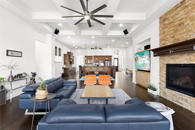 living room featuring dark wood-type flooring, beam ceiling, a towering ceiling, coffered ceiling, and a fireplace