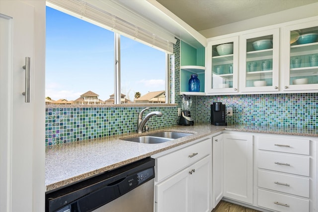 kitchen with white cabinetry, dishwasher, sink, decorative backsplash, and light stone counters