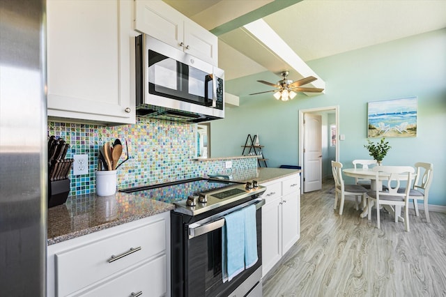 kitchen featuring light hardwood / wood-style flooring, appliances with stainless steel finishes, dark stone countertops, backsplash, and white cabinets