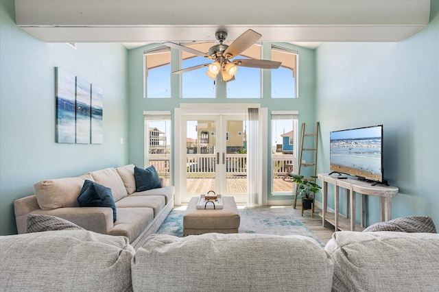 living room with ceiling fan, a wealth of natural light, light wood-type flooring, and french doors