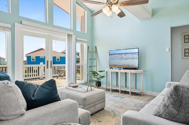 living room featuring a high ceiling, wood-type flooring, ceiling fan, and french doors