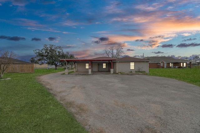 ranch-style home featuring a carport and a lawn