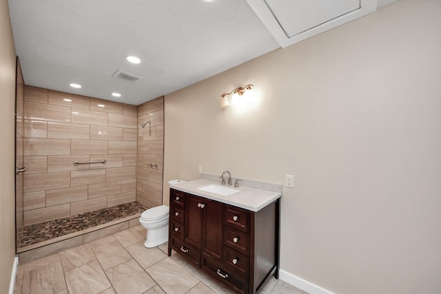 bathroom with vanity, tiled shower, and toilet