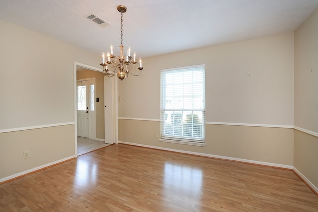 spare room with a notable chandelier and light hardwood / wood-style floors