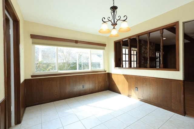 unfurnished dining area with wooden walls and a chandelier