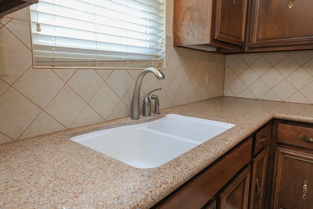 kitchen with sink, backsplash, and light stone countertops