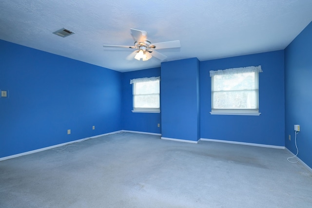 carpeted spare room featuring ceiling fan and a textured ceiling