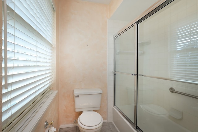 bathroom featuring enclosed tub / shower combo, toilet, and tile patterned flooring