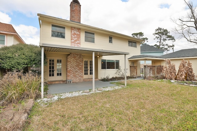 rear view of property with a patio area, french doors, and a lawn