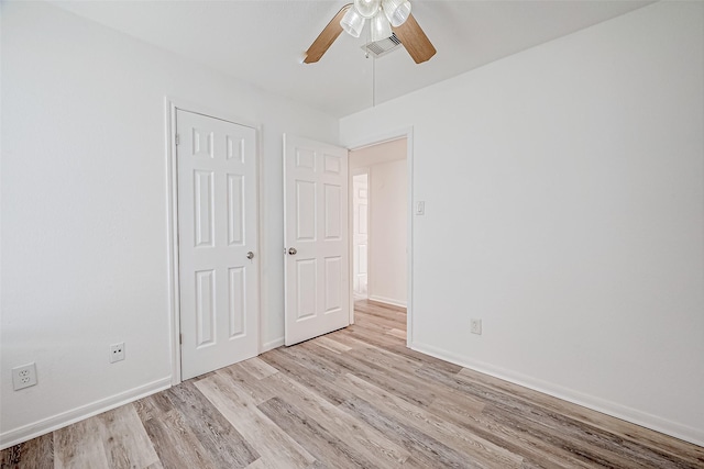 unfurnished bedroom with ceiling fan, light wood-type flooring, and a closet