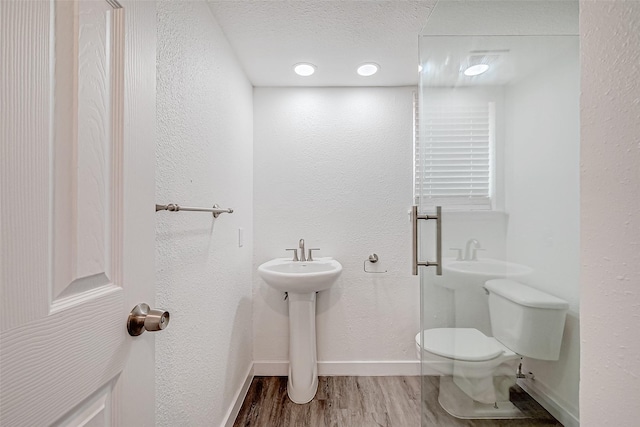 bathroom featuring hardwood / wood-style flooring, toilet, sink, and a textured ceiling