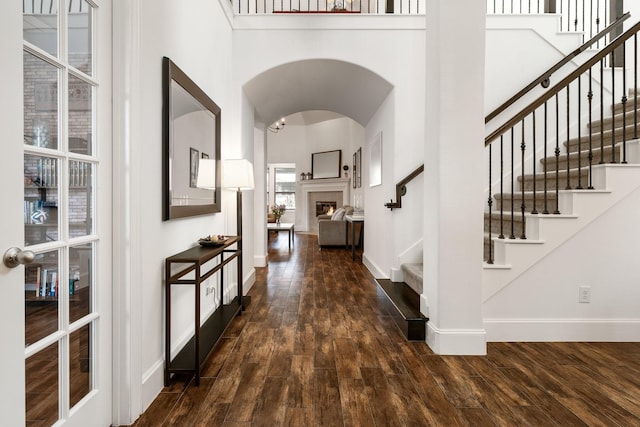 entrance foyer featuring a towering ceiling, dark hardwood / wood-style floors, and a tiled fireplace