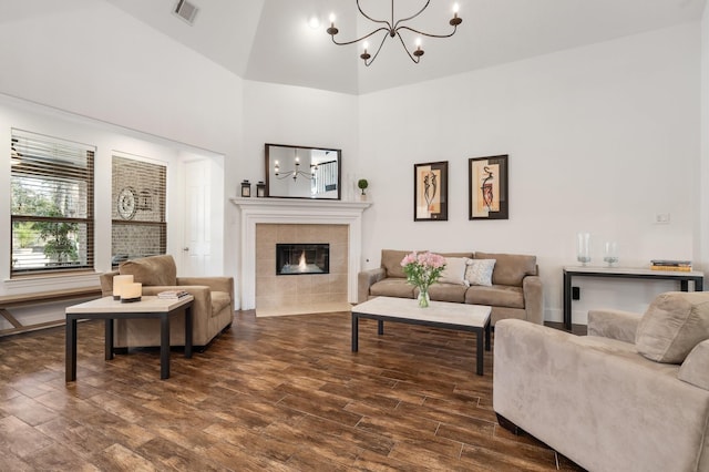 living room featuring an inviting chandelier, a fireplace, dark hardwood / wood-style floors, and a towering ceiling