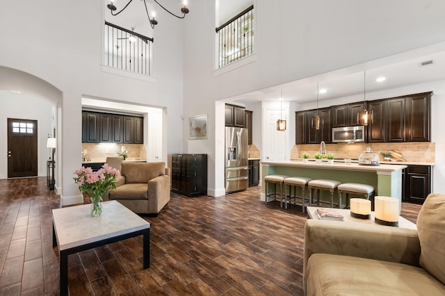 living room featuring dark wood-type flooring, a notable chandelier, and a wealth of natural light