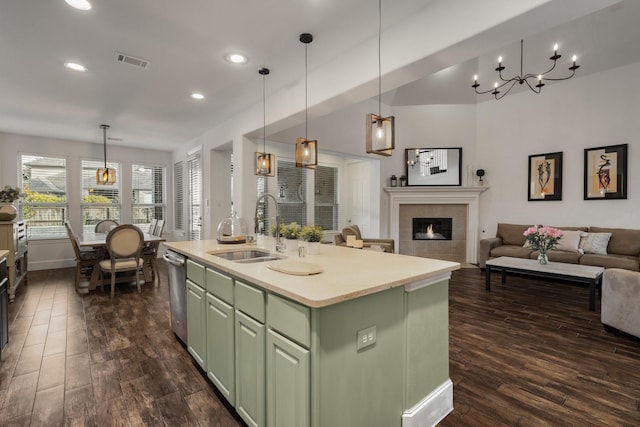 kitchen with pendant lighting, sink, green cabinets, a center island with sink, and stainless steel dishwasher