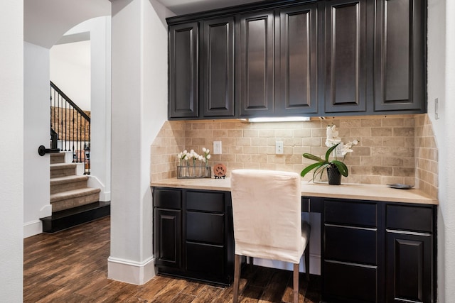 bar with dark hardwood / wood-style flooring, decorative backsplash, and built in desk