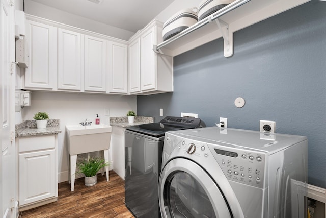 washroom featuring dark wood-type flooring, cabinets, and separate washer and dryer