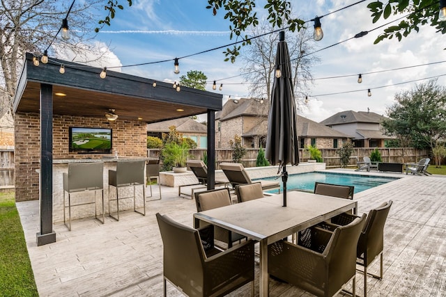 view of patio / terrace with a fenced in pool, ceiling fan, and exterior bar