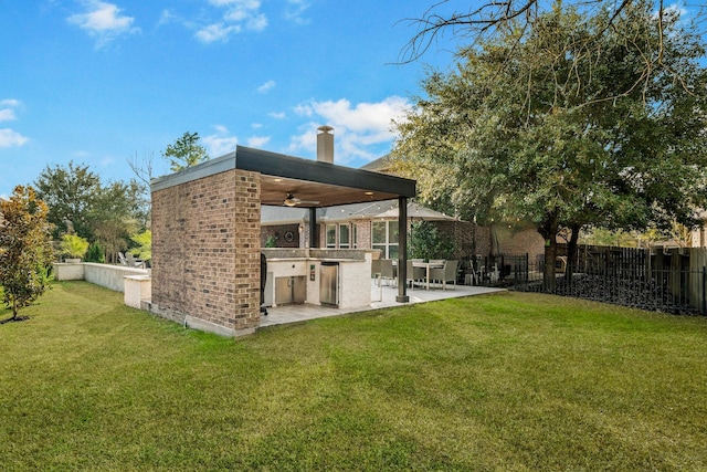 view of yard featuring a patio, ceiling fan, and an outdoor kitchen