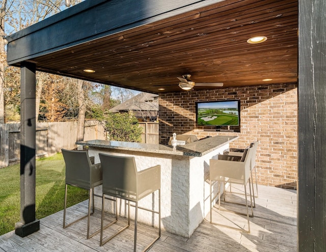 view of patio featuring a wooden deck, ceiling fan, and exterior bar