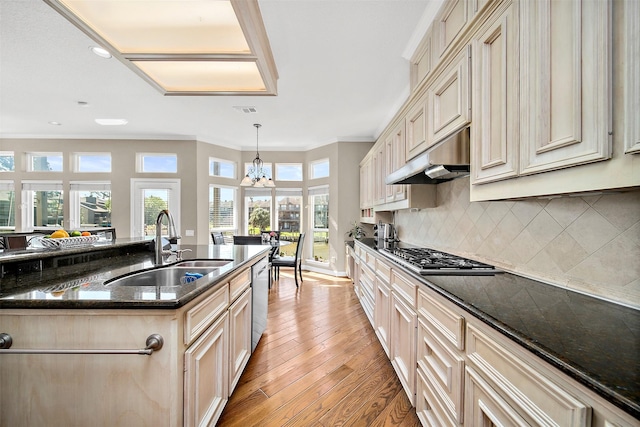 kitchen with sink, hanging light fixtures, stainless steel appliances, ornamental molding, and dark stone counters