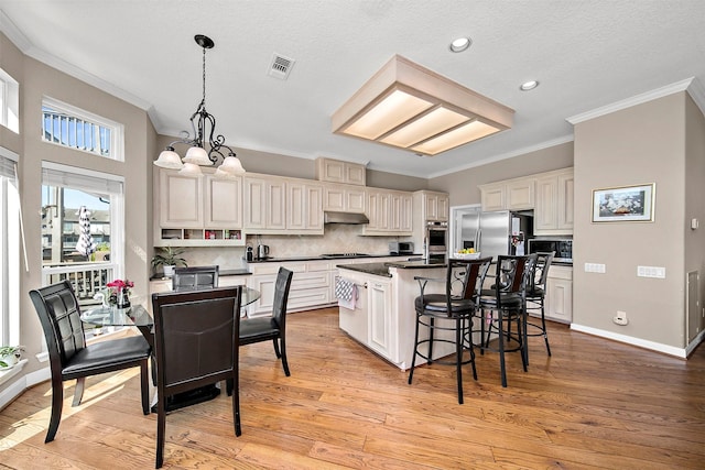 kitchen featuring pendant lighting, stainless steel appliances, a center island, and light wood-type flooring