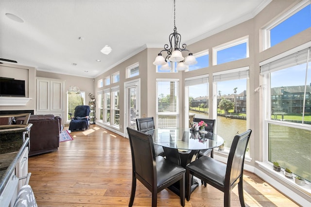 dining area with crown molding, an inviting chandelier, and light hardwood / wood-style flooring