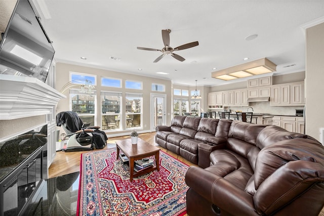 living room featuring hardwood / wood-style flooring, ornamental molding, ceiling fan, and a high end fireplace