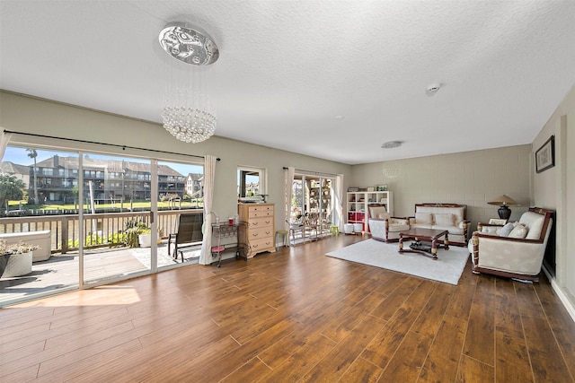 living area with dark hardwood / wood-style flooring, a notable chandelier, and a textured ceiling