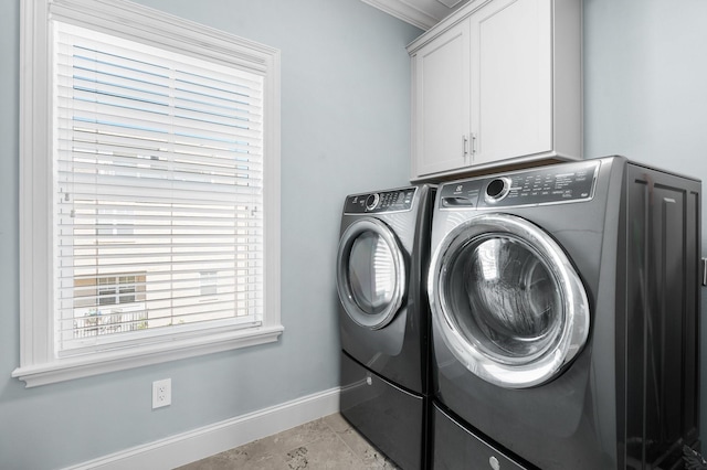 clothes washing area with cabinets and separate washer and dryer