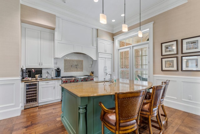 kitchen featuring white cabinetry, light stone counters, decorative light fixtures, and wine cooler