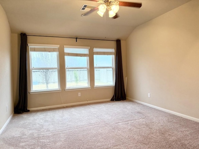 empty room with visible vents, baseboards, a ceiling fan, light colored carpet, and vaulted ceiling