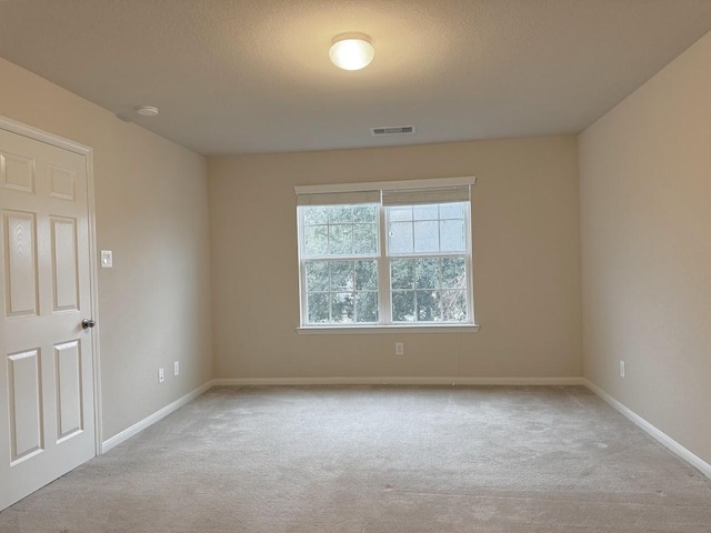 unfurnished room featuring light colored carpet, visible vents, baseboards, and a textured ceiling