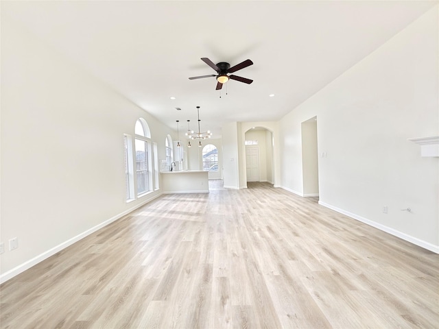 unfurnished living room with ceiling fan with notable chandelier and light hardwood / wood-style flooring