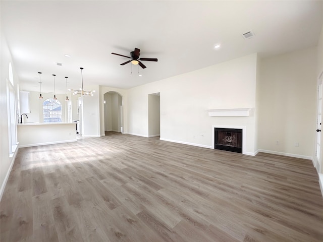 unfurnished living room with sink, ceiling fan, and light wood-type flooring