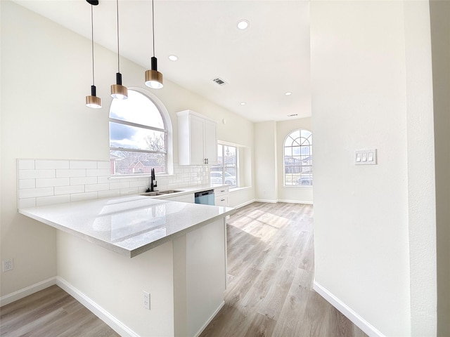 kitchen featuring white cabinetry, sink, decorative backsplash, light stone counters, and kitchen peninsula