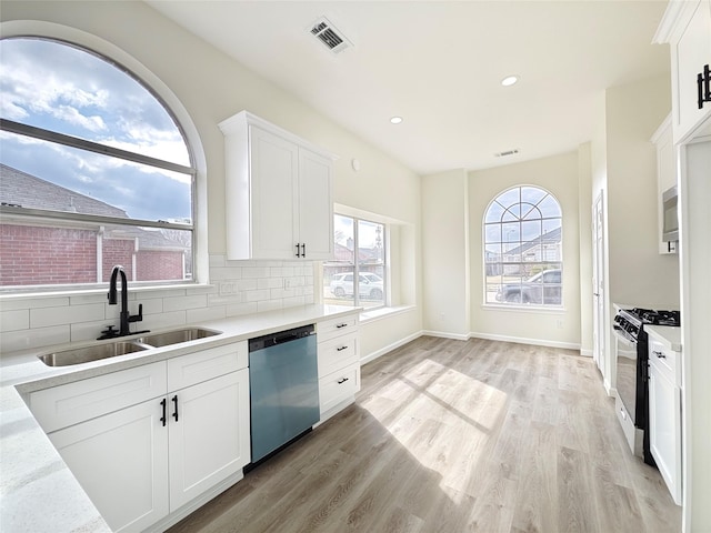 kitchen featuring sink, light hardwood / wood-style flooring, white cabinets, stainless steel appliances, and backsplash