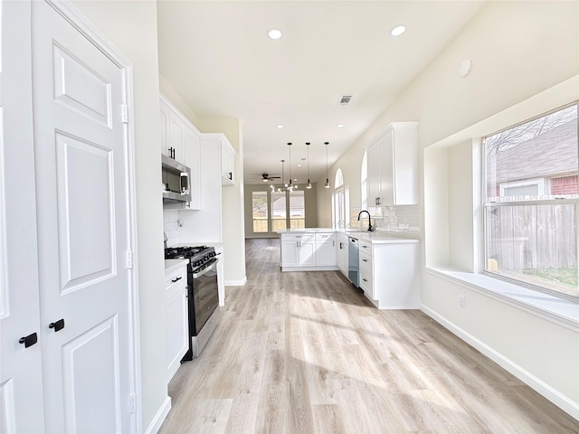 kitchen featuring decorative light fixtures, sink, white cabinets, kitchen peninsula, and stainless steel appliances