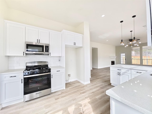 kitchen featuring white cabinetry, decorative light fixtures, tasteful backsplash, and stainless steel appliances