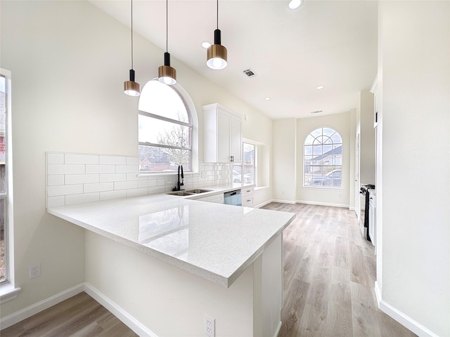 kitchen featuring dishwasher, white cabinetry, tasteful backsplash, decorative light fixtures, and kitchen peninsula