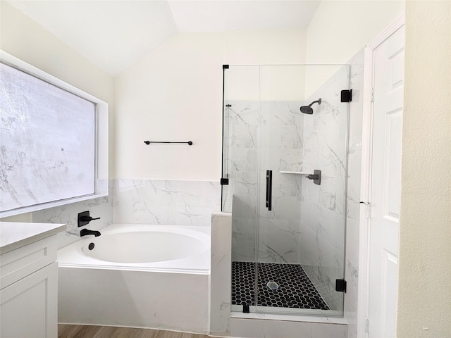 bathroom featuring vanity, independent shower and bath, vaulted ceiling, and hardwood / wood-style floors