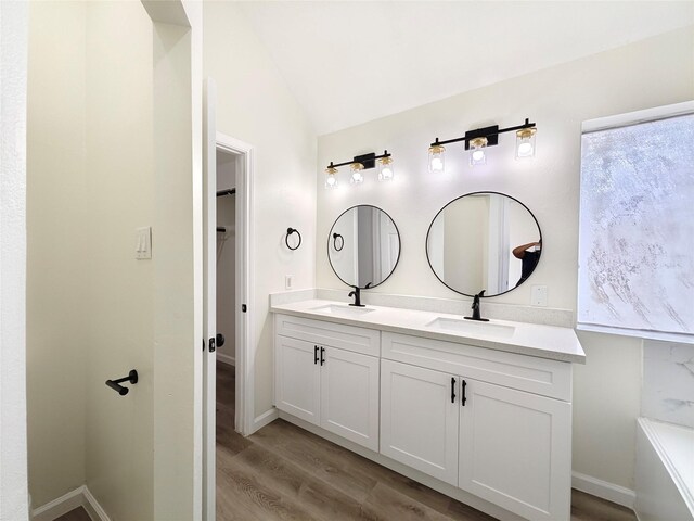 bathroom with vaulted ceiling, hardwood / wood-style floors, and vanity