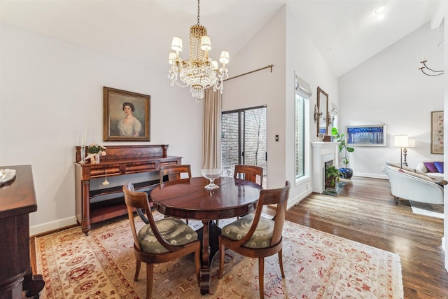 dining space with hardwood / wood-style flooring, a notable chandelier, and high vaulted ceiling