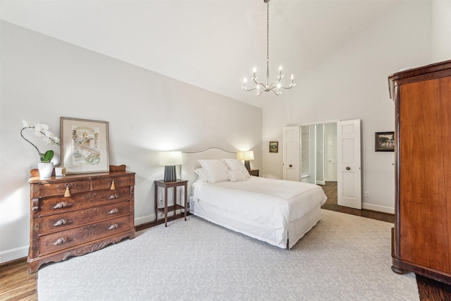 bedroom with wood-type flooring, high vaulted ceiling, and a chandelier