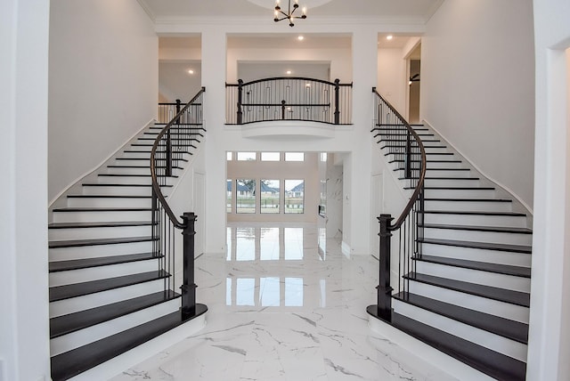 entrance foyer with a notable chandelier, a towering ceiling, and ornamental molding