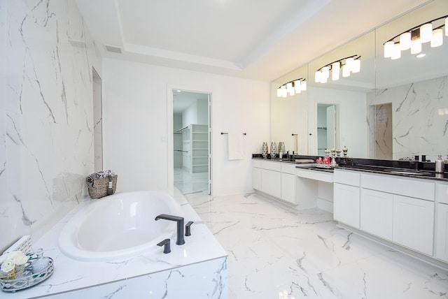 bathroom featuring a relaxing tiled tub, vanity, and a tray ceiling